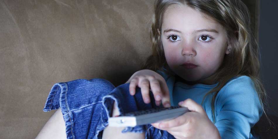 Young girl uses remote control while watching television